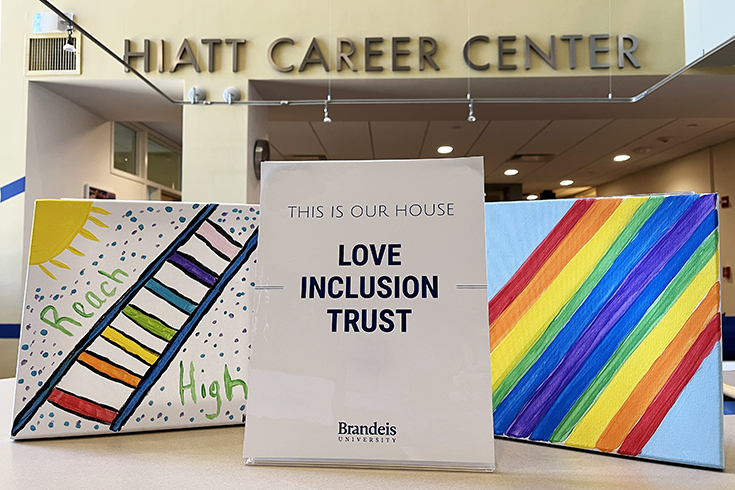 Two canvas drawings with rainbow colors surround a graphic at the Hiatt Career Center's front desk that reads, "This is Our House. Love. Inclusion. Trust."