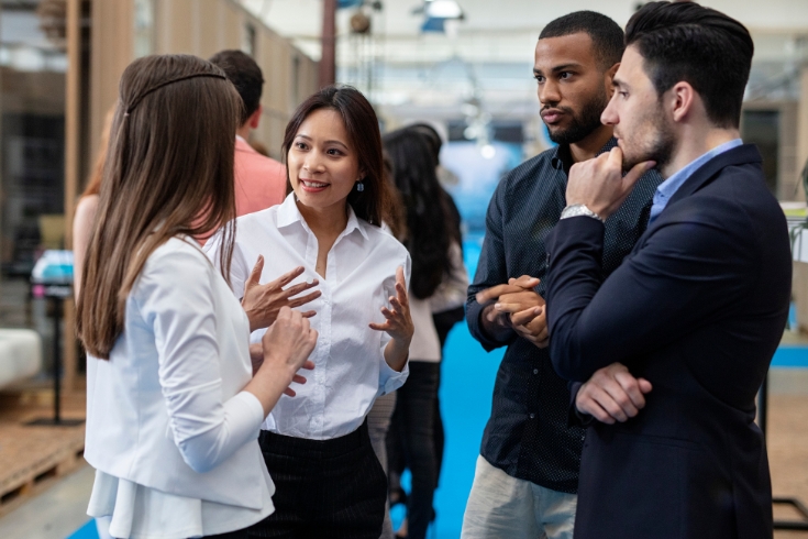 Four professionals stand in a circle chatting during a networking event.