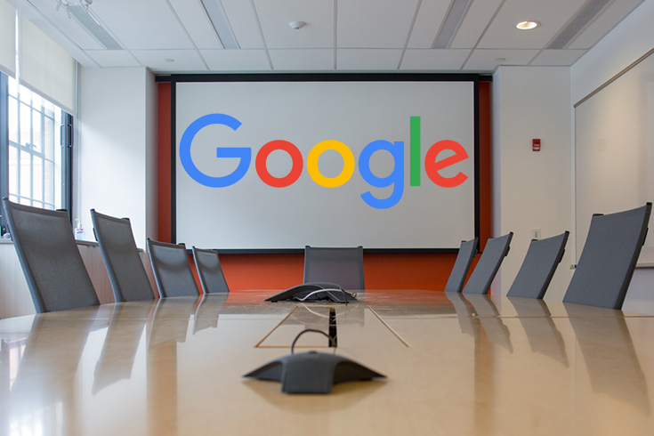 An empty conference room with the Google logo on a projector screen.