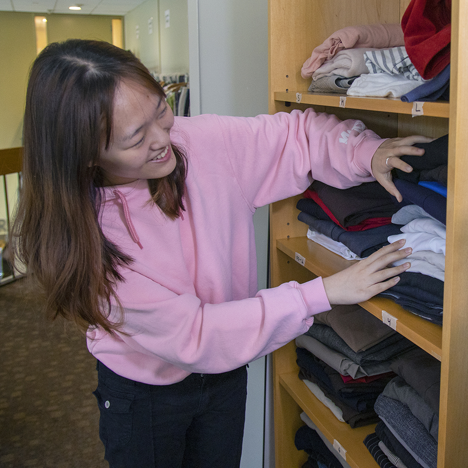 A student looks through sweaters in the Hiatt Career Closet