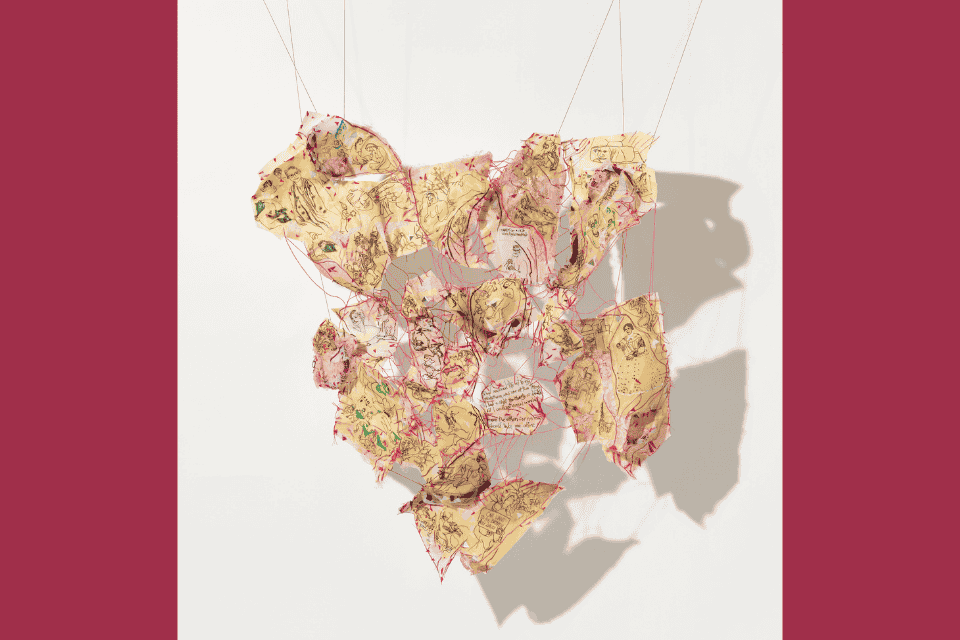 pieces of yellow paper with images of woman in black tied together with red thread