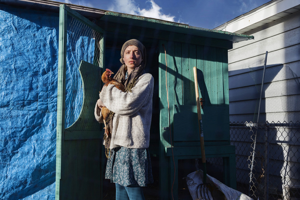 woman wearing head scarf holding chicken