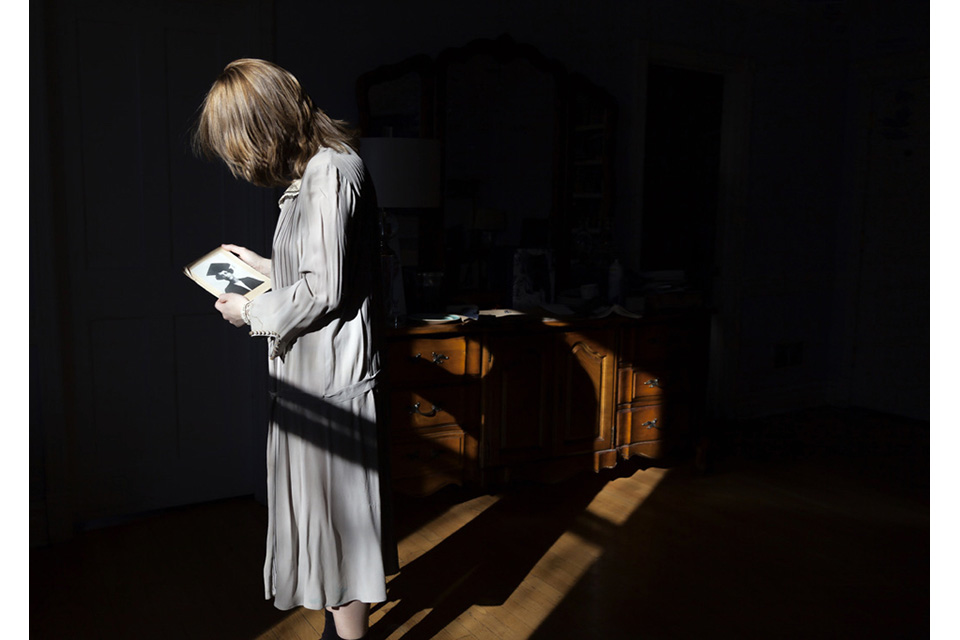 woman looking at photograph in dark bedroom
