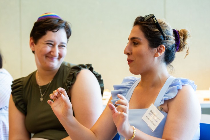 two people sitting next to each other, one is speaking to the group, the other is smiling at her