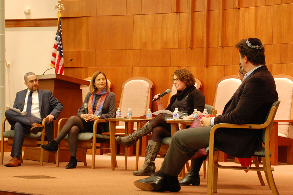 Dalia Wassner speaks with a microphone while three other speakers look on