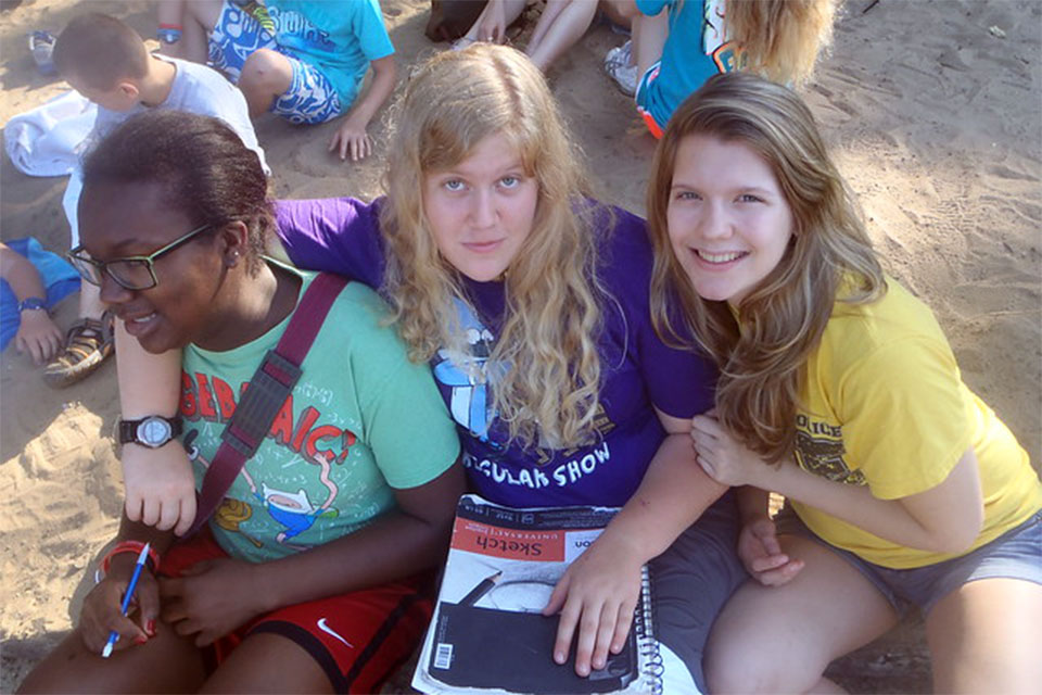 Campers at Camp Pinewood sitting together with arms around each other.