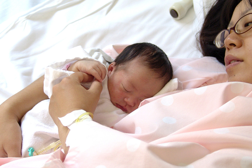 mother in hospital bed holding newborn girl