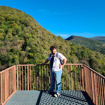 Aeryn standing on an overhang overlooking mountains with blue sky