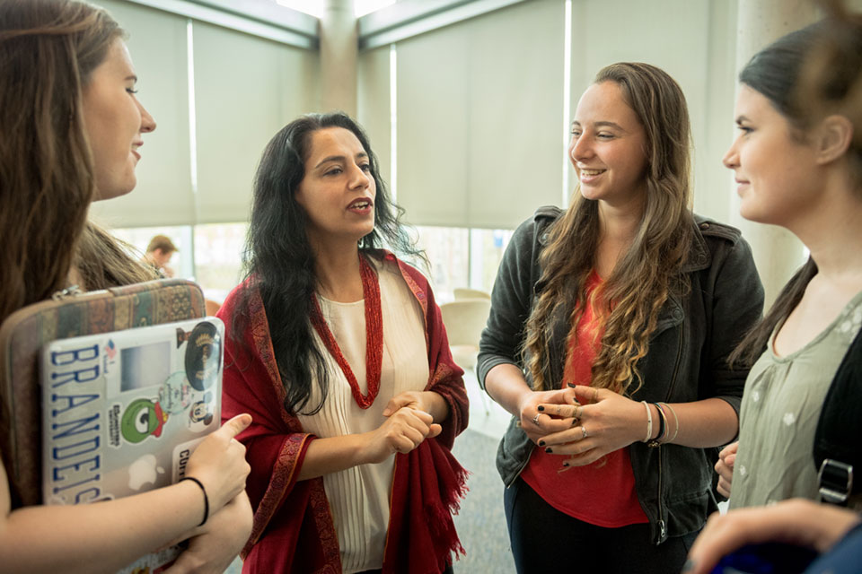 Professor Harleen Singh stands and talks with a group of students