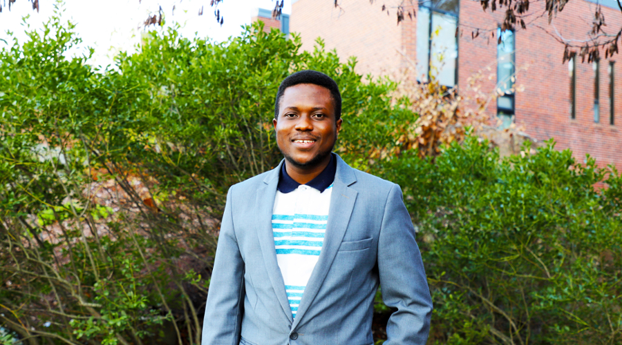 A portrait of Jonathan Korash in a white and blue shirt under a gray suit coat.