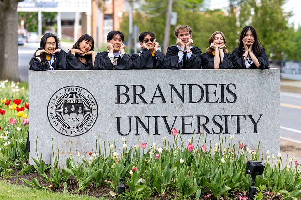 Students in caps and gowns smiling outside