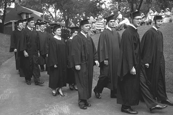 Students walking in caps and gowns outside