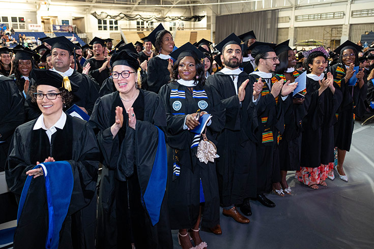 Students walking in caps and gowns inside Gosman