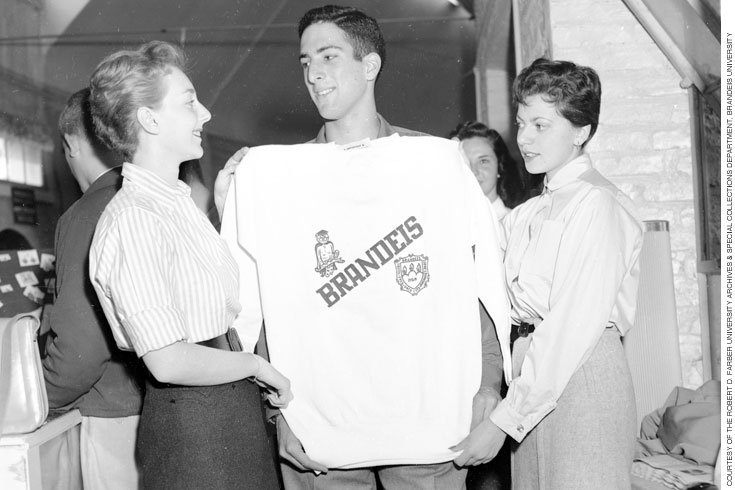 Three students holding a Brandeis sweatshirt
