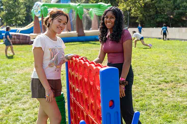 Two students on campus playing a giant game of connect 4
