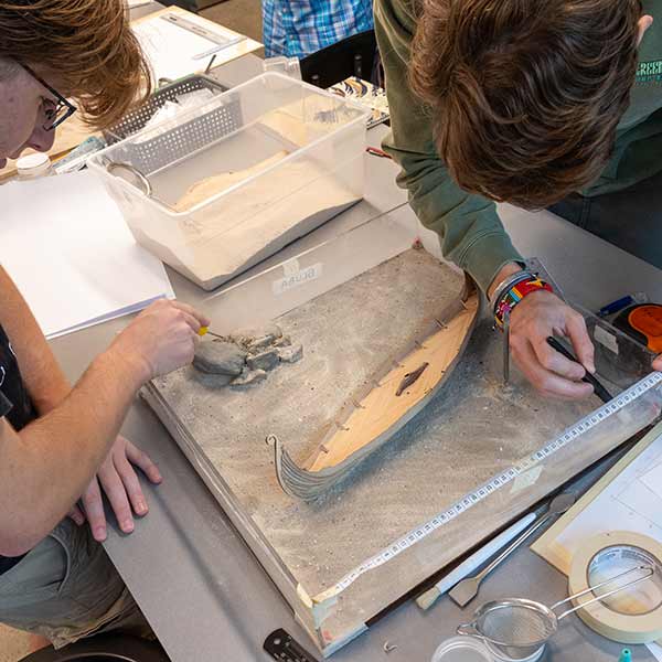 Students work on a mock shipwreck archeological excavation 
