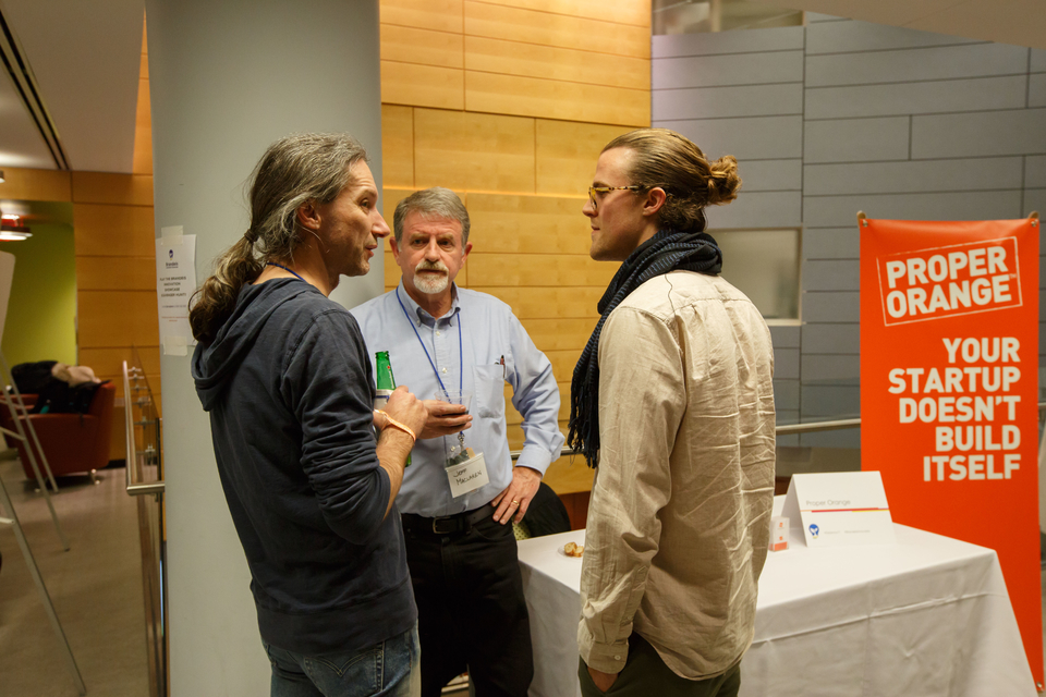 three men talking in front of a white table