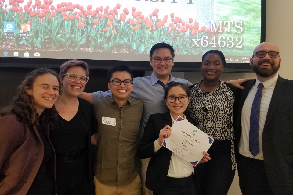 group of people smiling, holding a prize certificate