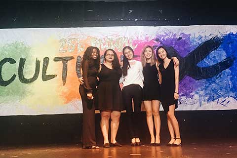 Five students stand in front of a colorful Culture X banner