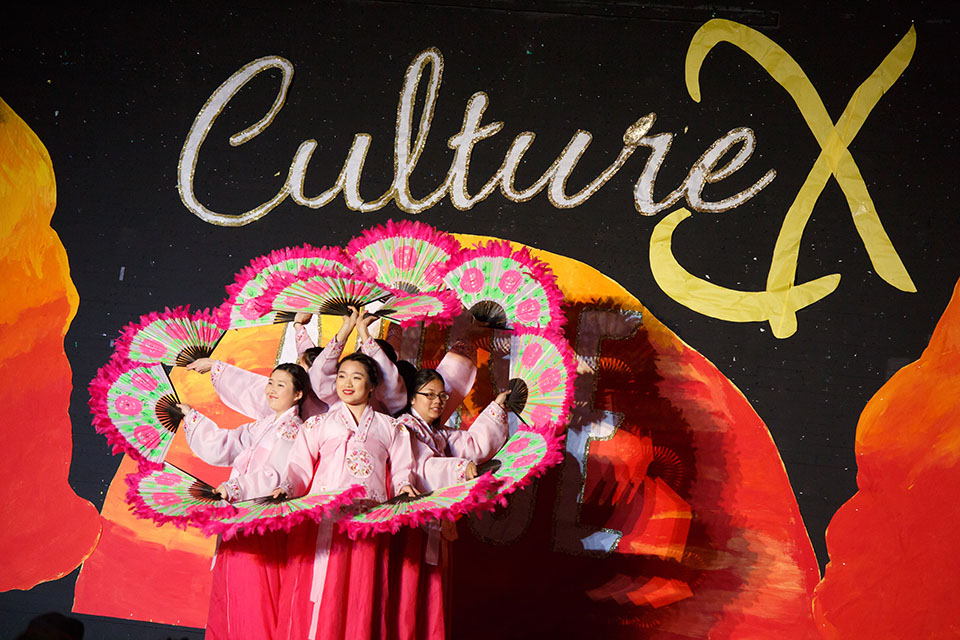 seven students pose in front of colorful culture x banner