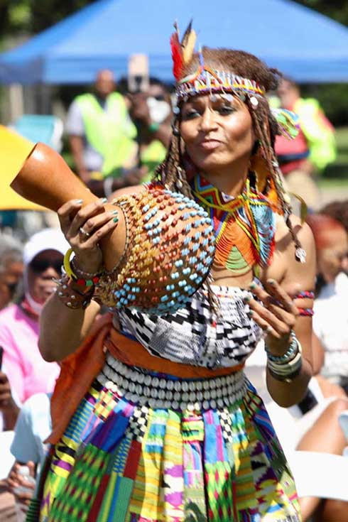 A woman dances, dressed in native attire playing the shakarey
