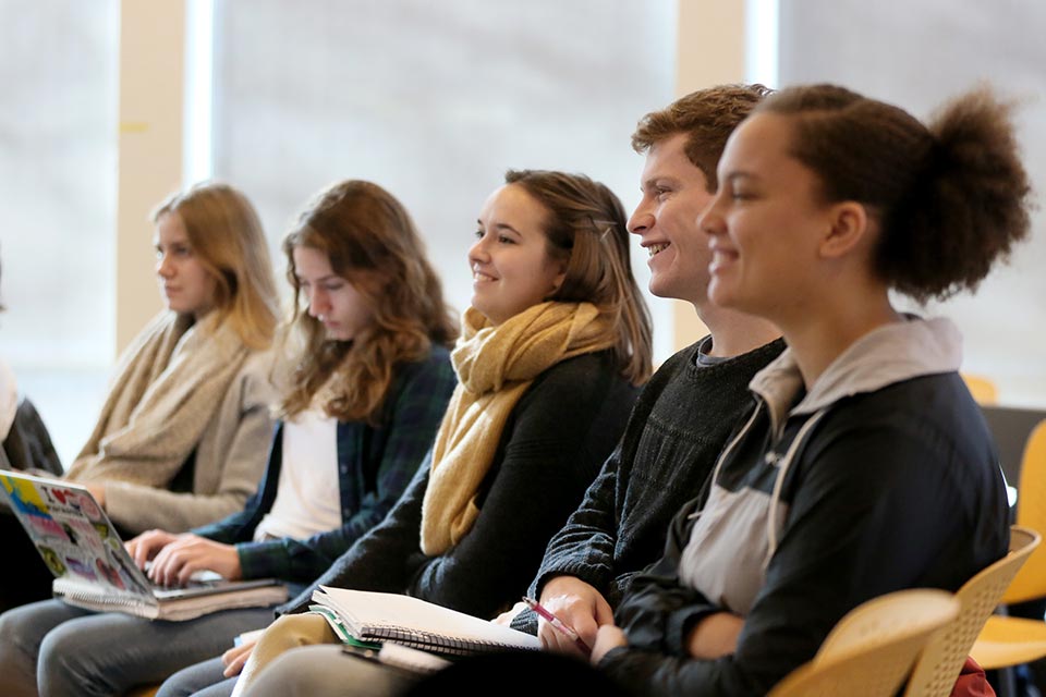 Students seated in a lecture, one student speaking