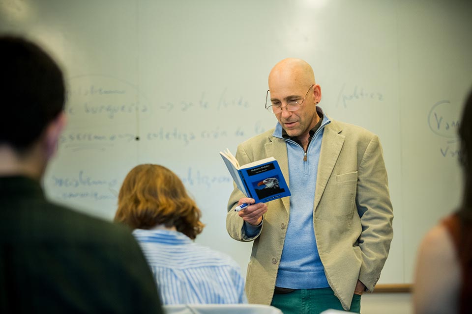 Professor Fernando Rosenberg reading from a book in front of a class