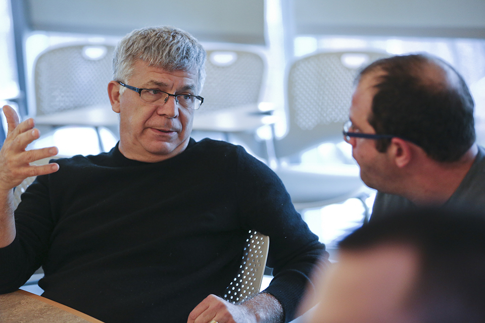 Two men speaking at a table in a conference room.