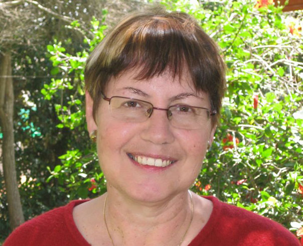 Photo of a middle-aged woman in a red sweater with close-cropped hair and a smile