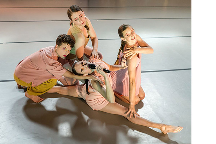 Four dancers posing together on a wooden dance floor