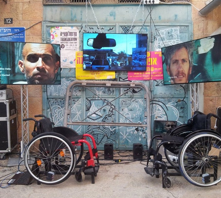 Two empty wheelchairs and three large TV screens