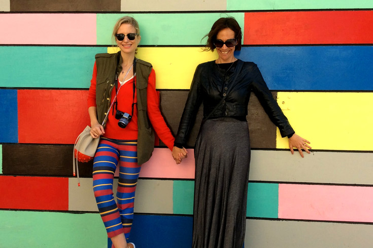 Two women holding hands against a colorful background