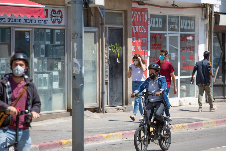 Masked pedestrians and cyclists on a Tel Aviv street
