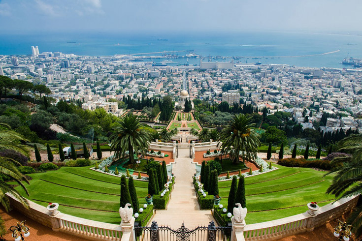Panoramic view of hillside garden opening to views of a city and, below it, the sea
