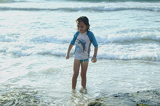 Crying child standing in the surf