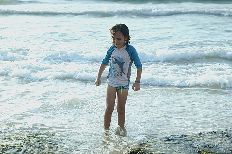 Child standing in the surf on a beach