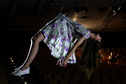 Girl lying prone, levitating under a ceiling