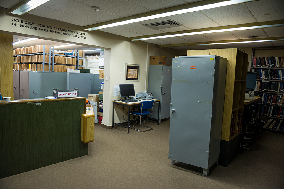 A room with a desk, library stacks, cabinets, and books