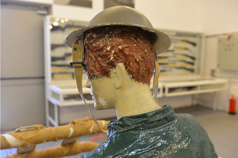 Painted sculpture of a human head and shoulders, with a hat, seen from behind
