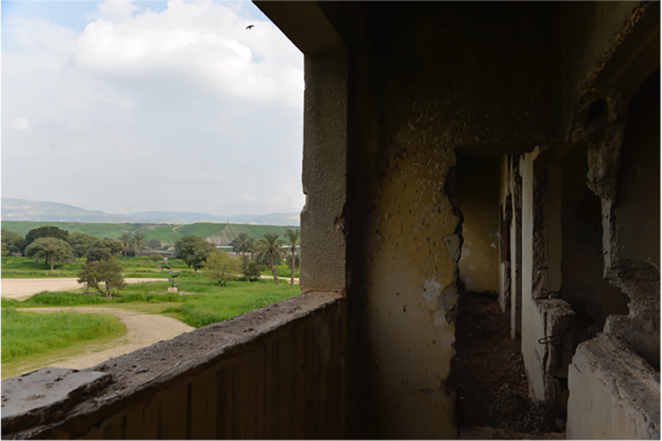 Bombed out building with view of trees, dirt paths and distant hills