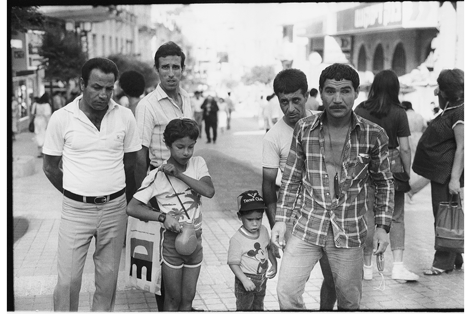 Men and boys standing on a stone-paved pedestrian area