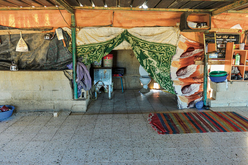 A toilet room is revealed behind pinned-back curtains or rugs