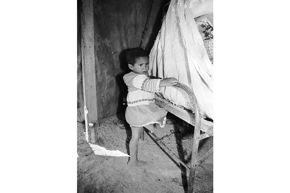 Child holding onto a metal rail attached to a piece of furniture