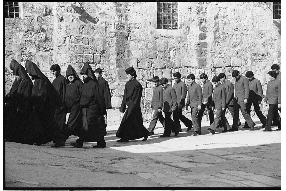Procession of hooded men followed by boys