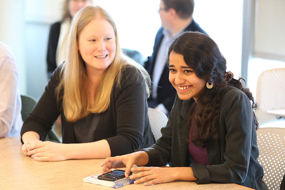 Doctoral candidates Karen Spira and Maham Ayaz sitting at the Schusterman Seminar table