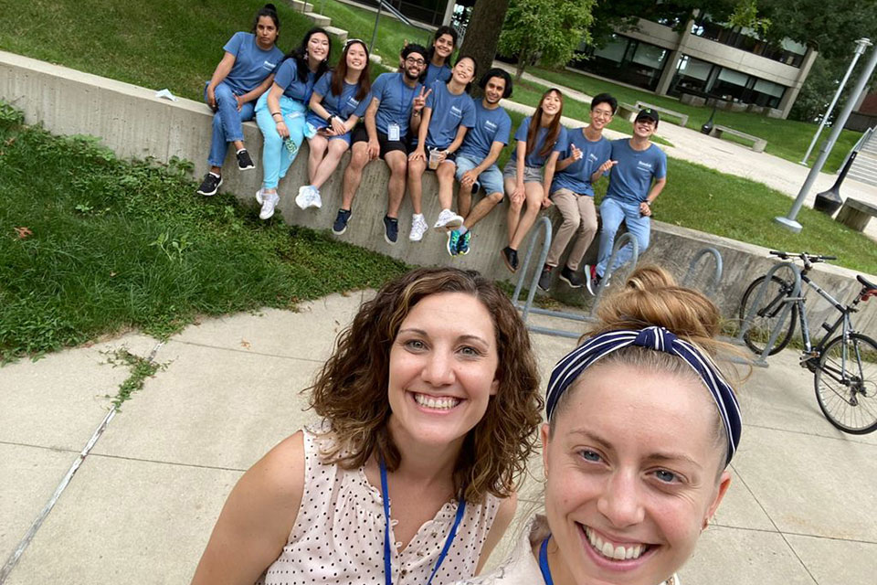 Staff take a selfie with a group of international students behind them