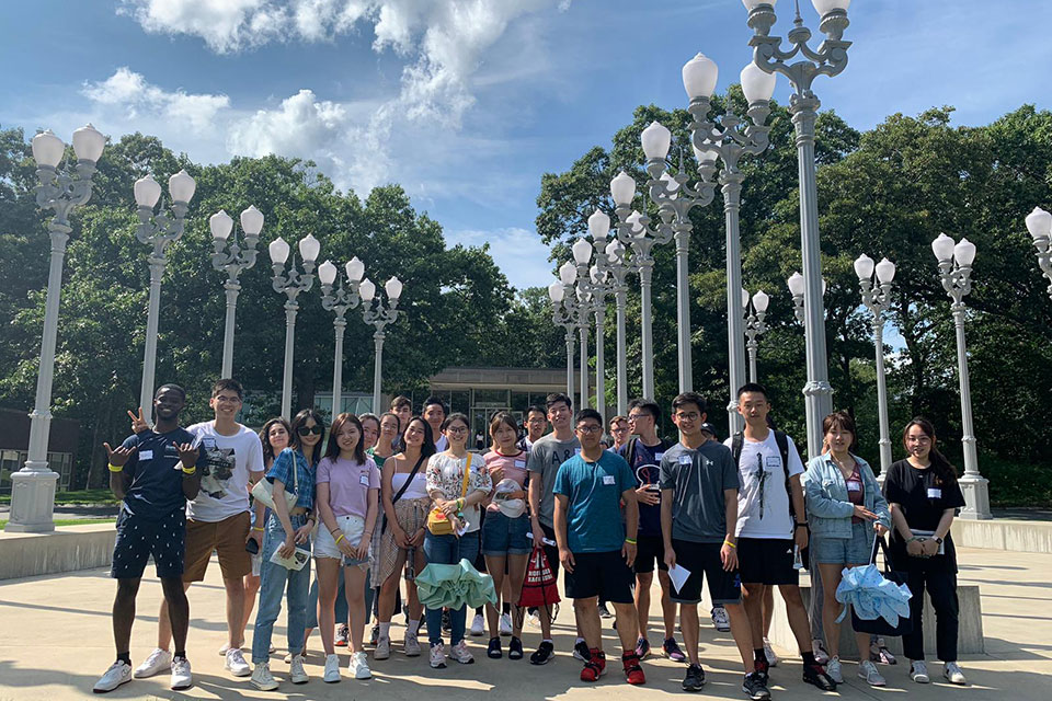 A group of international students gathers at the Light of Reason statue