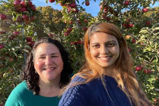 Staff and student smiling while apple picking