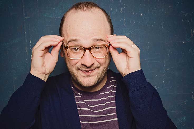 Josh Gondelman adjusting his eyeglasses
