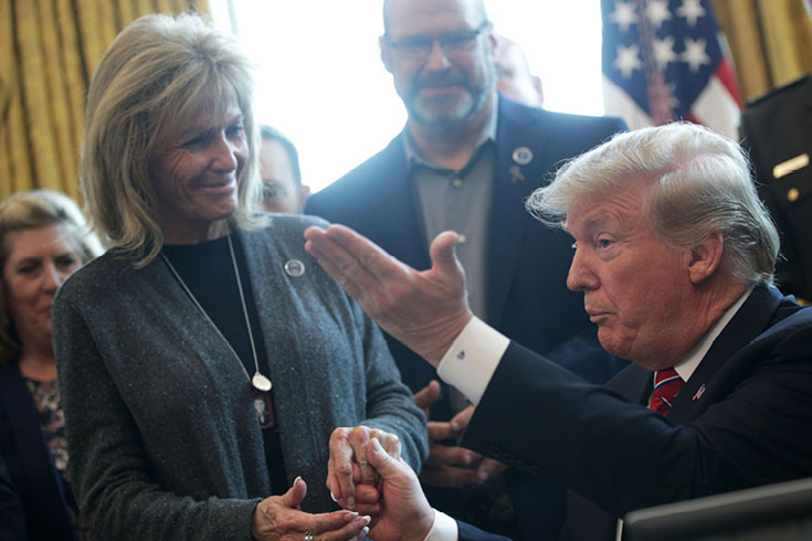 Pres. Donald Trump in the Oval Office flocked by several people